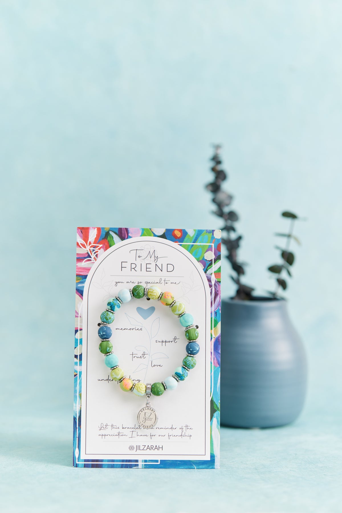 Friend Bracelet on its To My Friend card beside a small blue vase